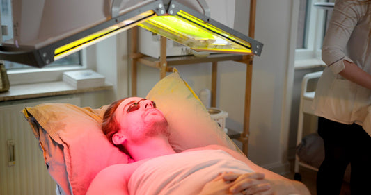 Liggende mand får lysbehandling af en lampe der lyser på hans ansigt