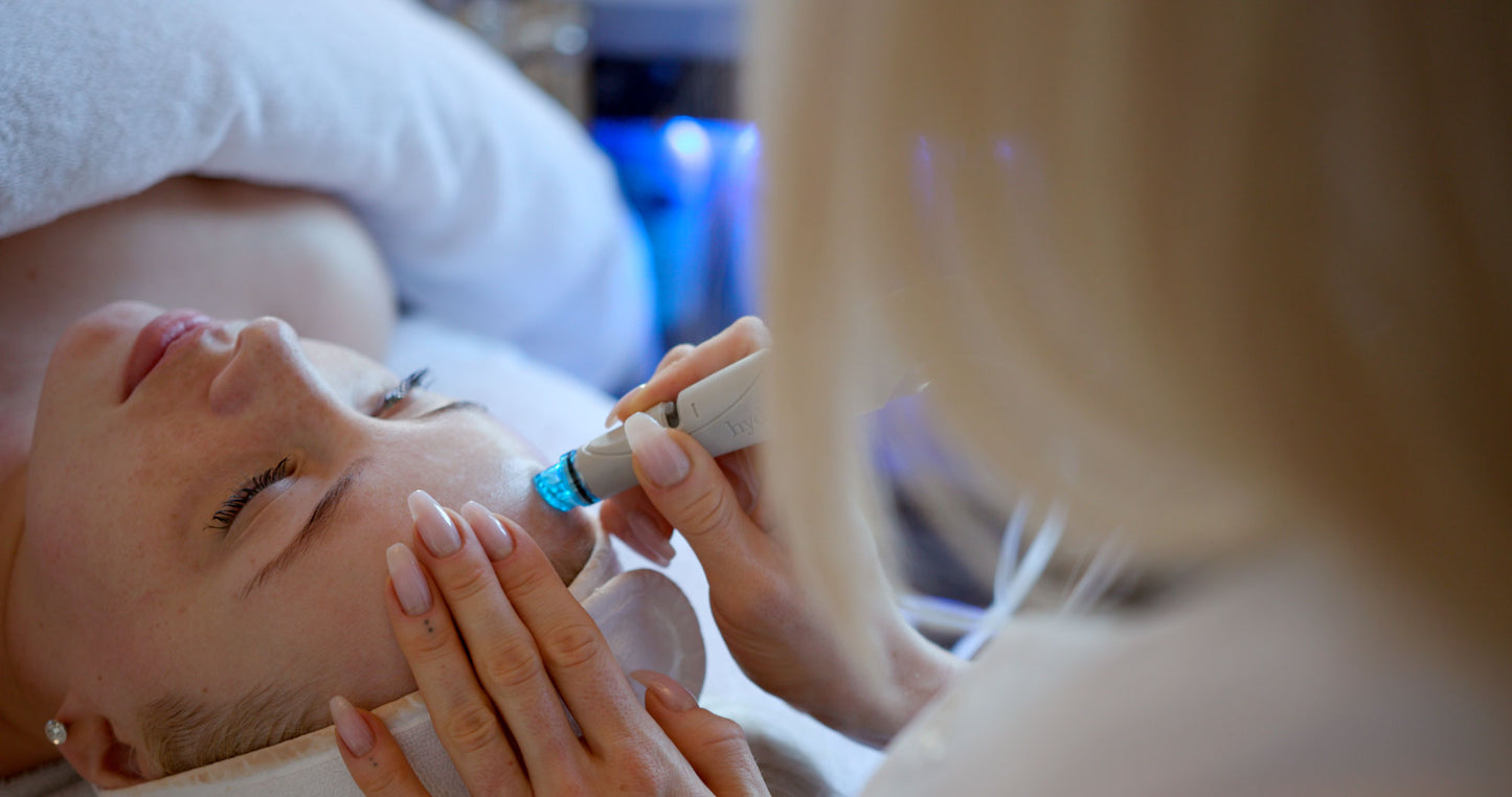 Liggende kvinde får hydra facial ansigtsbehandling af en anden kvinde